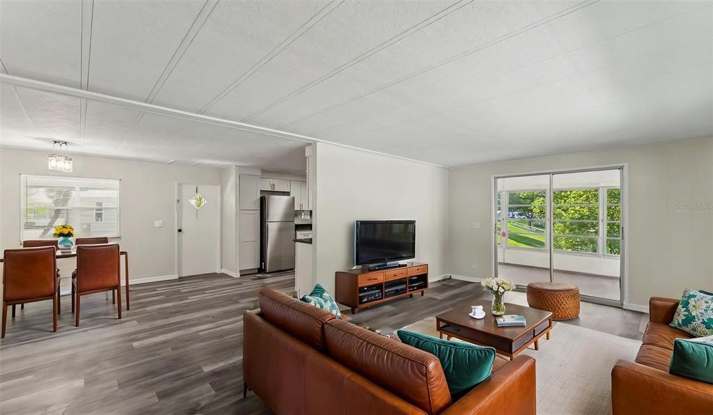 An open-concept living and dining area features wood-look flooring, light walls, and a sliding door — 2055 S FLORAL AVENUE UNIT 324, BARTOW, FL