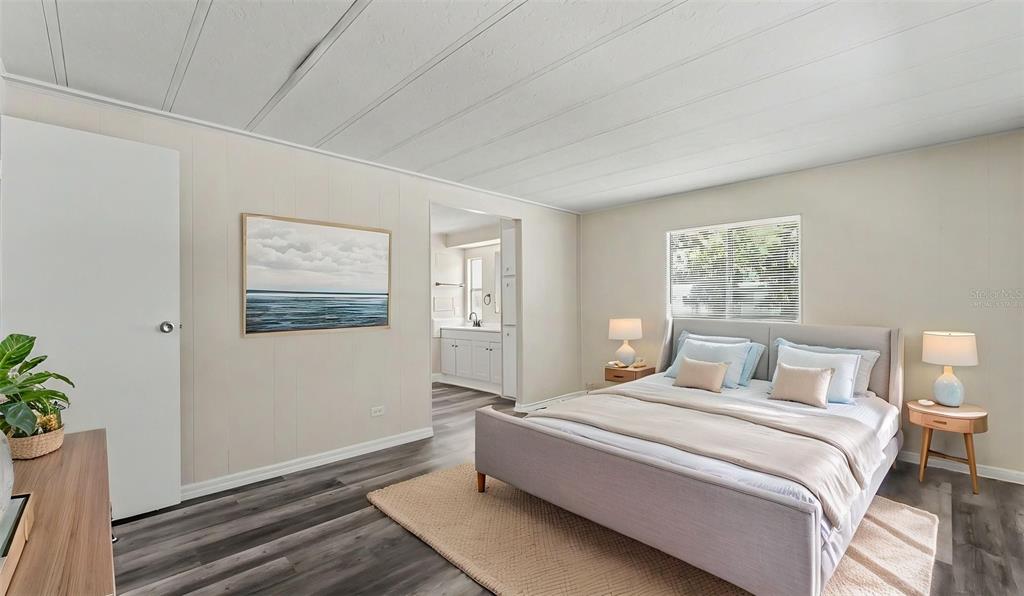 A bedroom with light walls, wood-look flooring, a bed, and an attached bathroom — 2055 S FLORAL AVENUE UNIT 324, BARTOW, FL