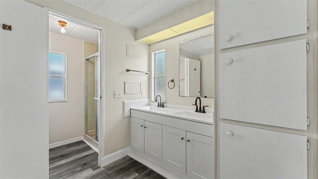 A bathroom features a double vanity with white cabinets, a mirror, and a walk-in shower — 2055 S FLORAL AVENUE UNIT 324, BARTOW, FL