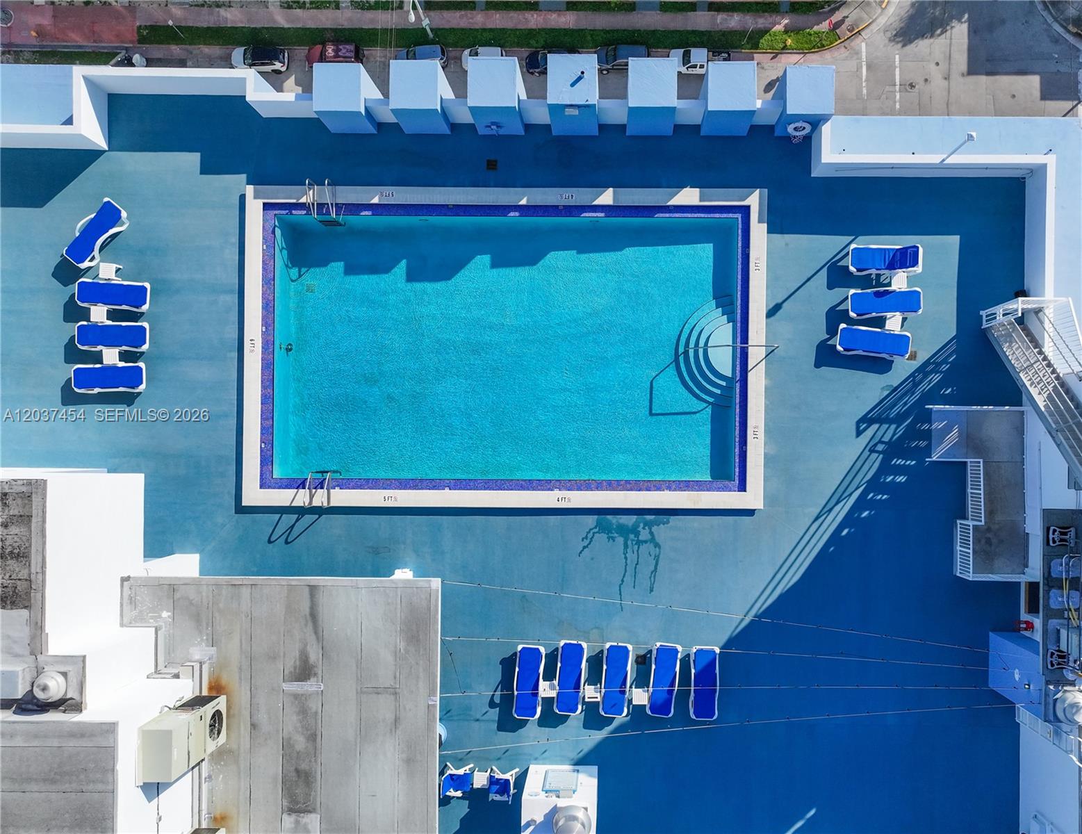 An aerial view shows a rectangular swimming pool surrounded by blue lounge chairs on a deck — 401 69th St # 313, Miami Beach FL 33141, MIAMI BEACH, FL