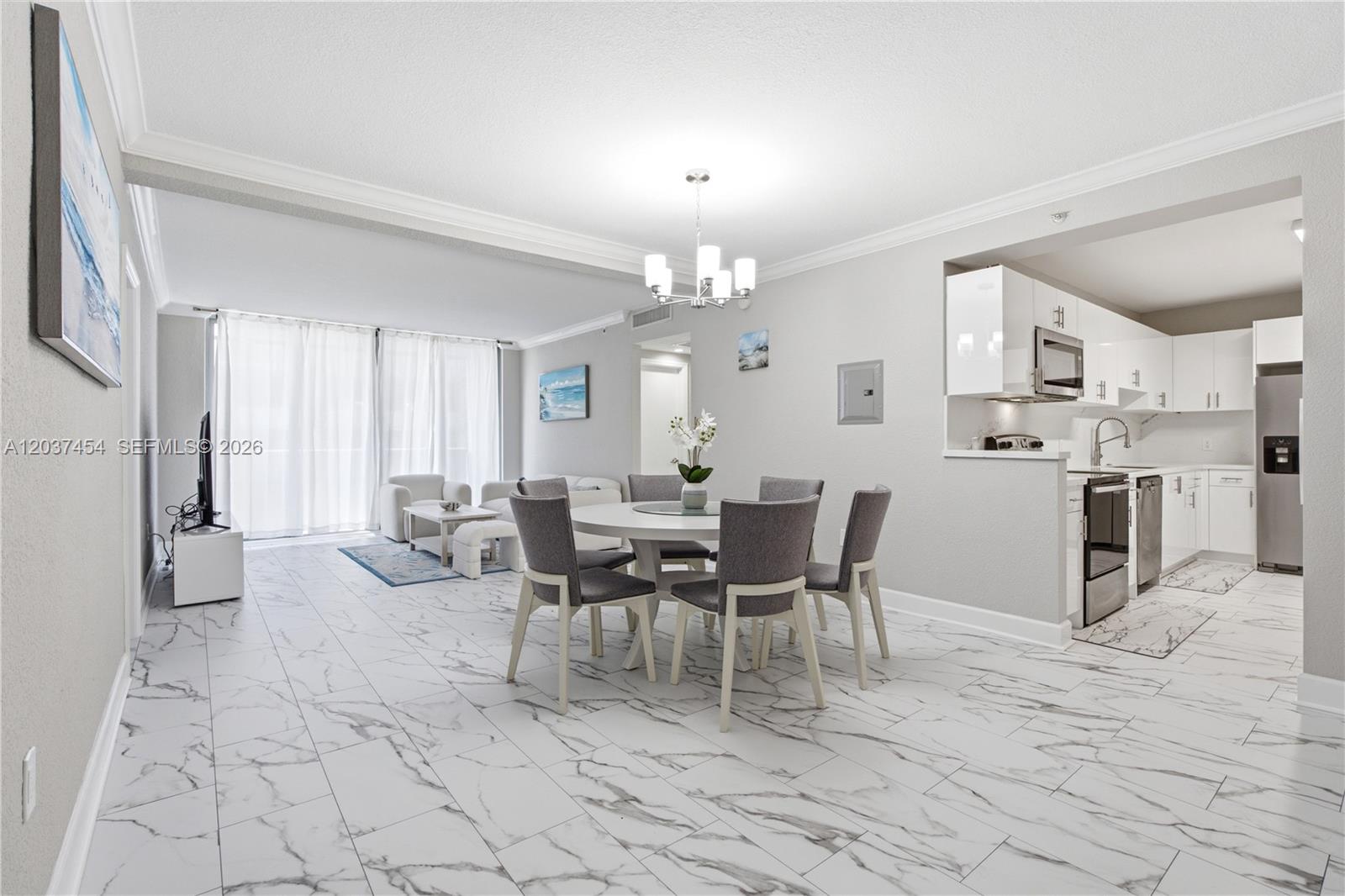 An open-concept dining and living area features white marble-look tile flooring and a modern kitchen — 401 69th St # 313, Miami Beach FL 33141, MIAMI BEACH, FL