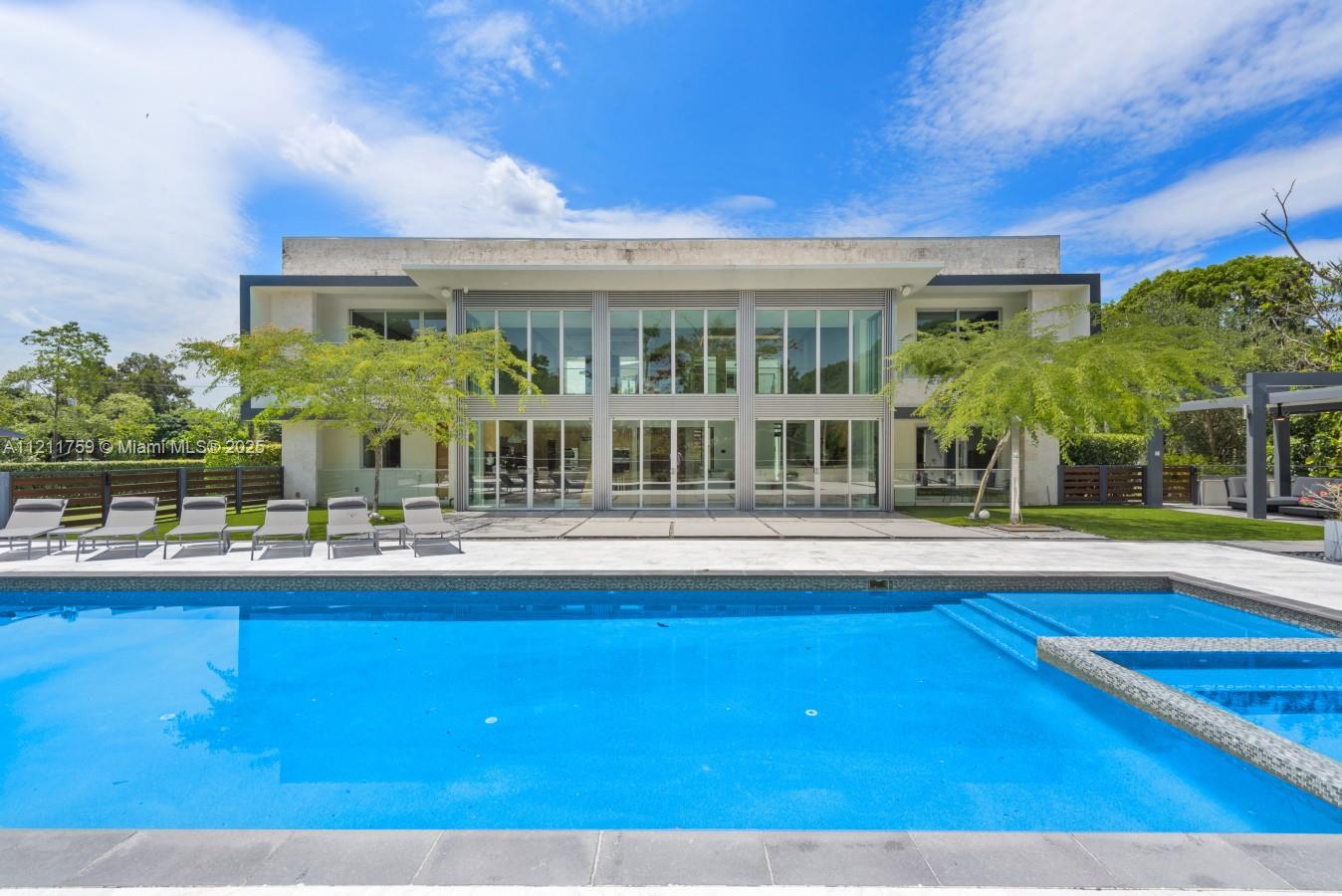 A modern two-story house features a large swimming pool and patio with lounge chairs — 14305 Stirling Rd, Southwest Ranches FL 33330, SOUTHWEST RANCHES, FL
