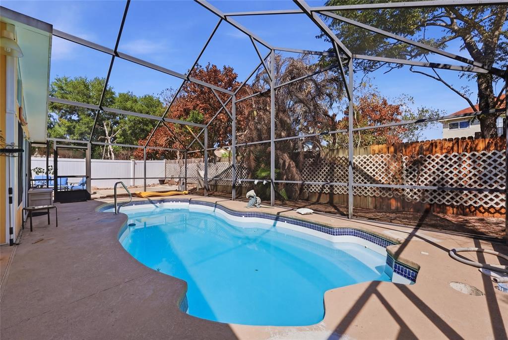 A screened-in backyard patio features a swimming pool with a concrete deck and lattice fencing — 12315 KENTON COURT, ORLANDO, FL