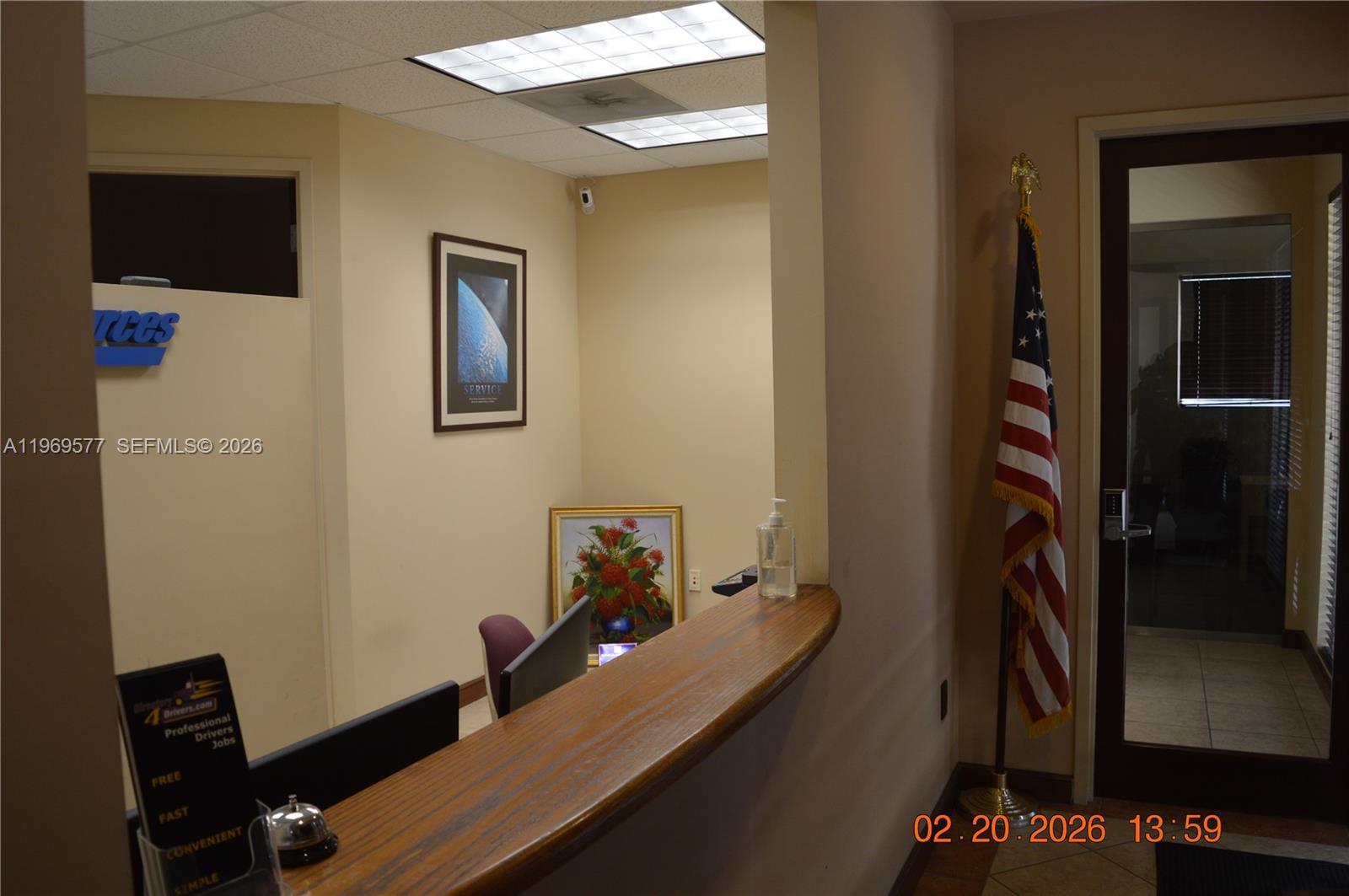 A reception area features a wooden counter, a desk bell, and an American flag — 7779 NW 146th St # 8, Miami Lakes FL 33016, MIAMI LAKES, FL