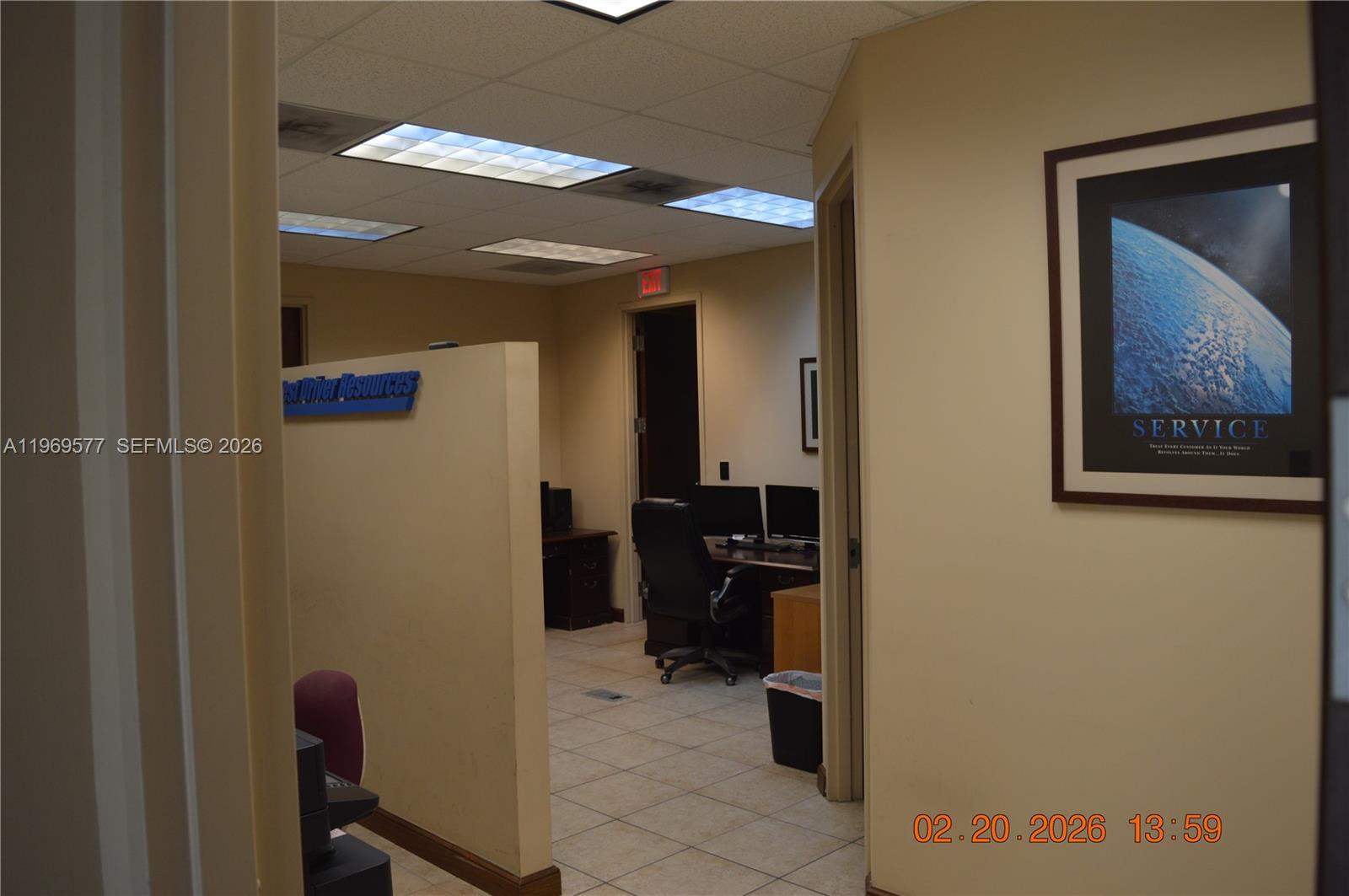 An office space features a partial wall, tiled flooring, drop ceiling, and a framed wall poster — 7779 NW 146th St # 8, Miami Lakes FL 33016, MIAMI LAKES, FL