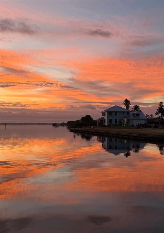 A two-story house sits on a waterfront lot during a vibrant orange and pink sunset — 2380 VANCE TERRACE, PORT CHARLOTTE, FL