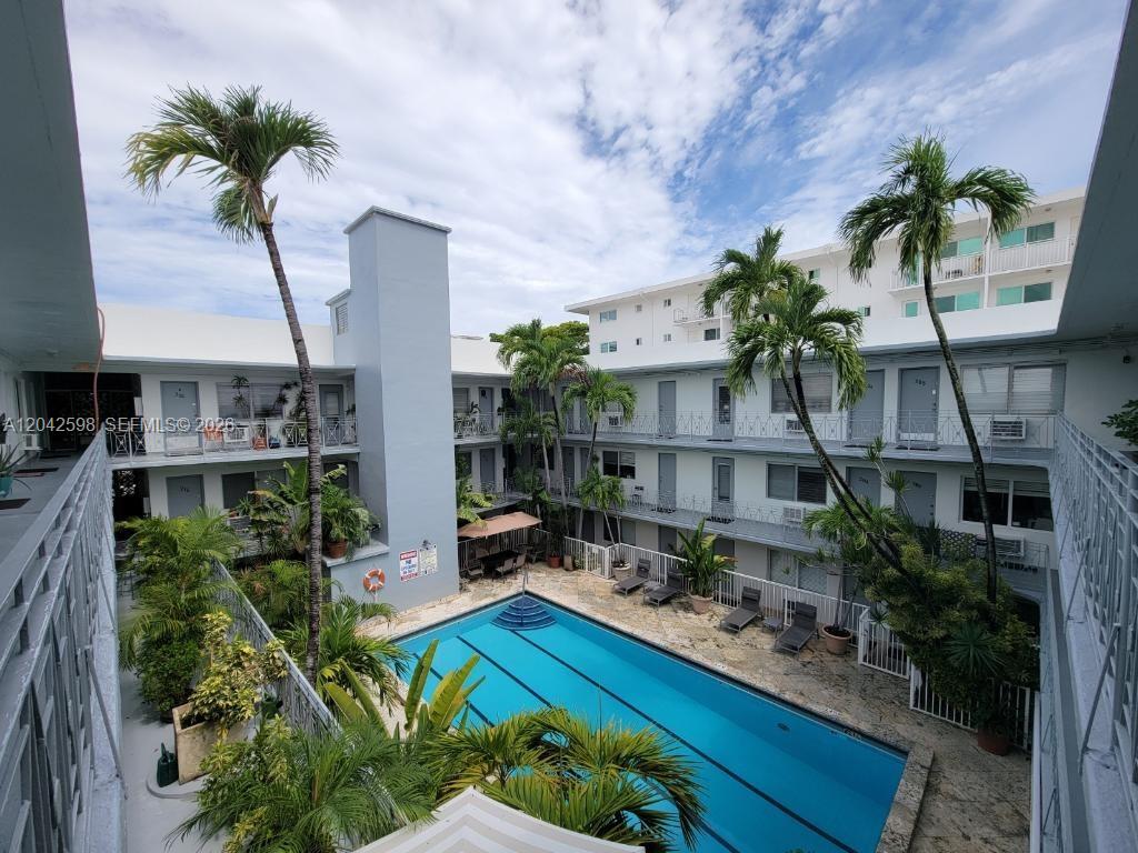An elevated view of a swimming pool surrounded by a multi-story apartment building and palms — 835 Lenox Ave # 102, Miami Beach FL 33139, MIAMI BEACH, FL