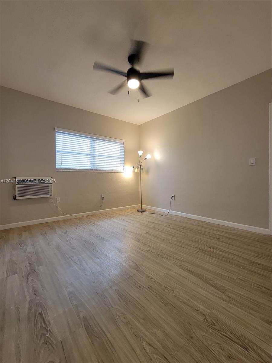 An empty room features light-colored wood-look flooring, a ceiling fan, and a floor lamp — 835 Lenox Ave # 102, Miami Beach FL 33139, MIAMI BEACH, FL