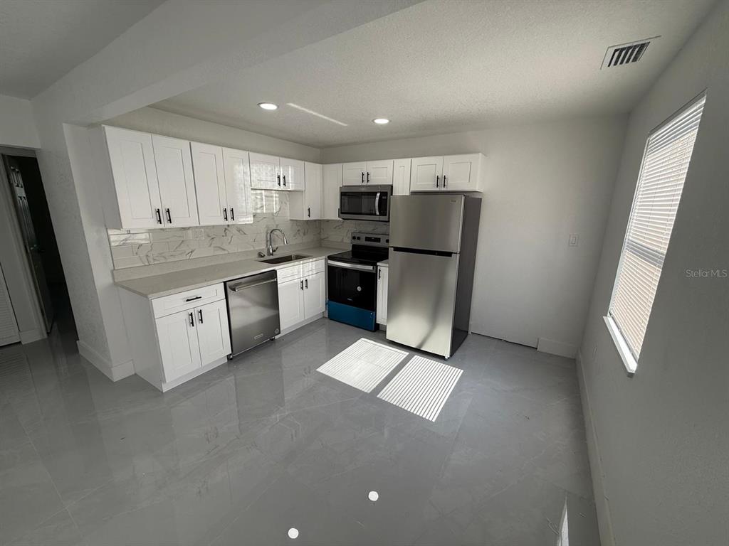 A kitchen with white cabinets, stainless steel appliances, and light gray tile flooring — 427 40TH AVENUE S, ST PETERSBURG, FL