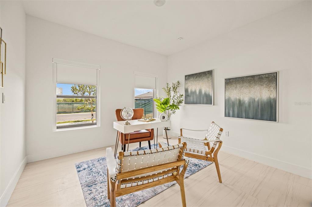 A bright home office features a white desk, two woven chairs, and two large wall paintings — 6450 OCTAVE STREET DRIVE, MASCOTTE, FL