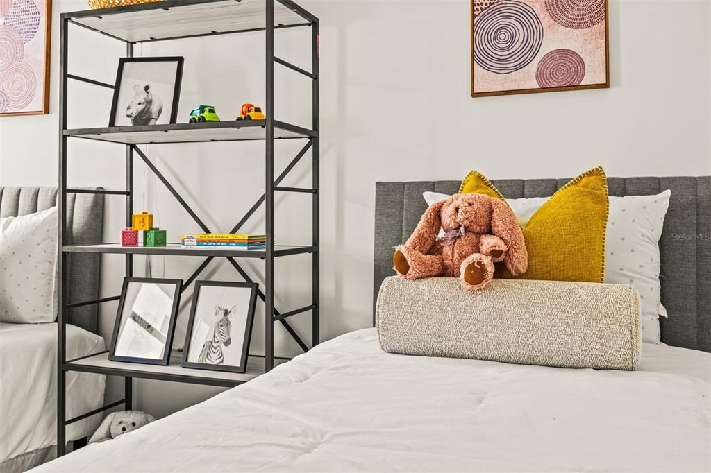 A bedroom features two beds, a metal shelving unit, and framed wall art — 6450 OCTAVE STREET DRIVE, MASCOTTE, FL