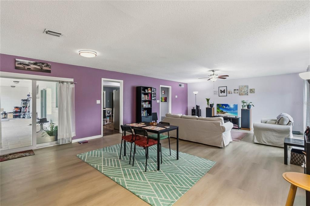 A living and dining area features purple walls, light wood flooring, and a green rug — 1489 MAGELLAN CIRCLE UNIT 603, ORLANDO, FL