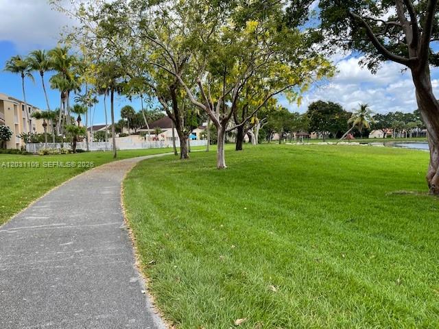 A paved walking path winds through a grassy park area with trees and residential buildings — 15275 SW 107th Ln # 102, Miami FL 33196, MIAMI, FL