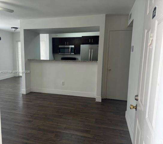 An interior view shows a kitchen with dark cabinets and stainless steel appliances behind a counter — 15275 SW 107th Ln # 102, Miami FL 33196, MIAMI, FL