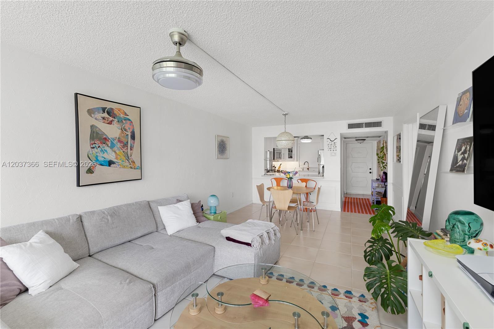 A living room with a gray sectional sofa, glass coffee table, and adjacent dining area — 9495 Evergreen Pl # 103, Davie FL 33324, DAVIE, FL