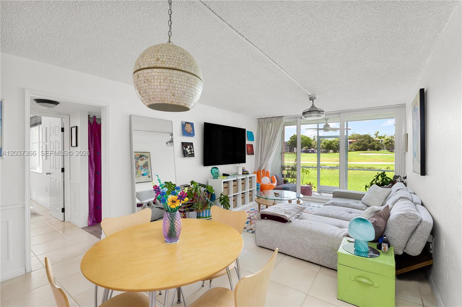 A living and dining area features a light wood table, sectional sofa, and floor-to-ceiling windows — 9495 Evergreen Pl # 103, Davie FL 33324, DAVIE, FL