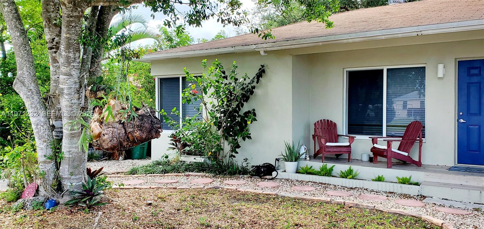 A single-story house exterior features a front porch with two red chairs and landscaping — 265 NE 116th St, Miami FL 33161, MIAMI, FL