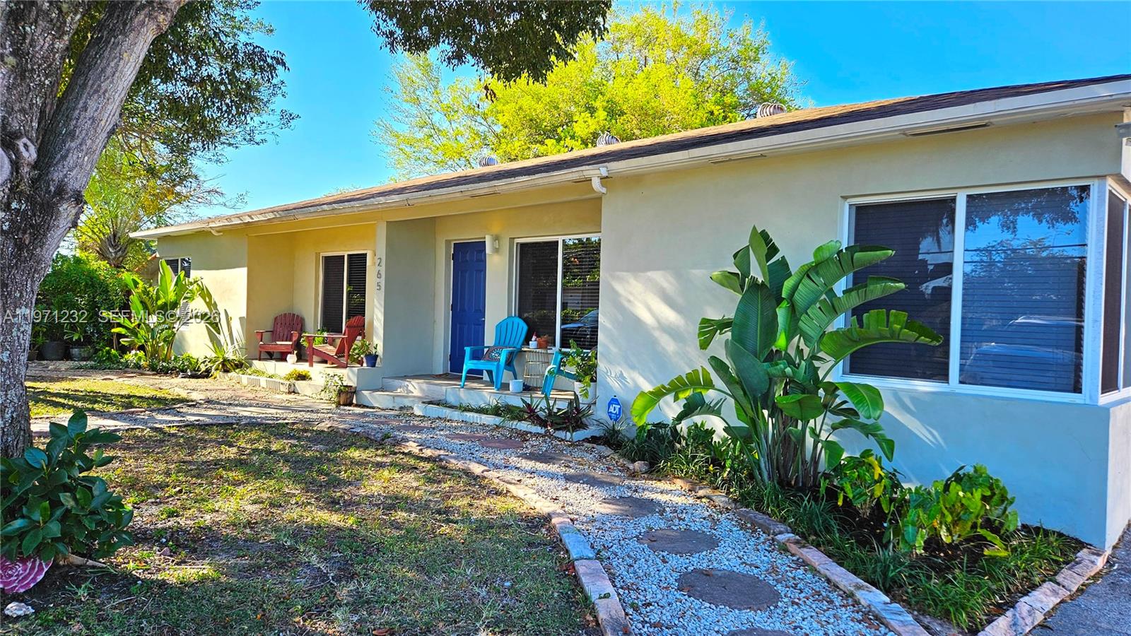 A single-story house with a blue front door, gravel walkway, and large tropical plants — 265 NE 116th St, Miami FL 33161, MIAMI, FL