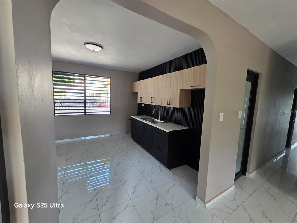 A kitchen features black base cabinets, light wood upper cabinets, and white marble-patterned tile flooring — 290 CALLE CEIBA, PATILLAS, PR