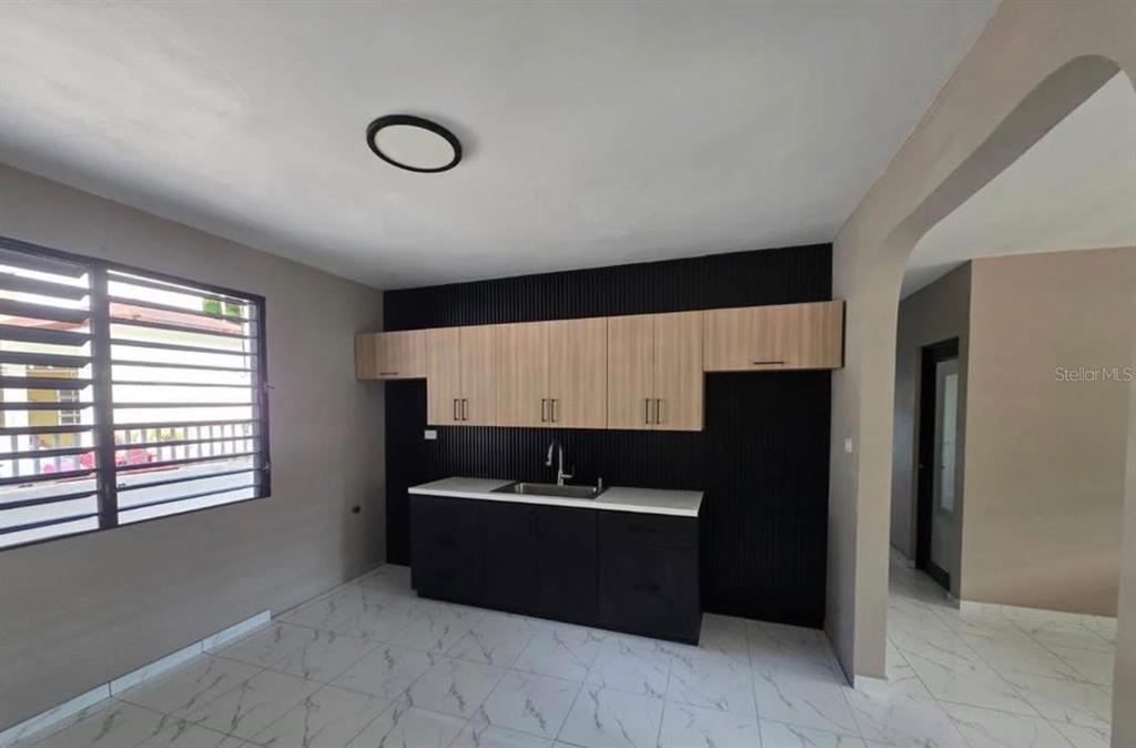 A kitchen features black slatted walls, light wood cabinets, a white countertop, and tiled floors — 290 CALLE CEIBA, PATILLAS, PR