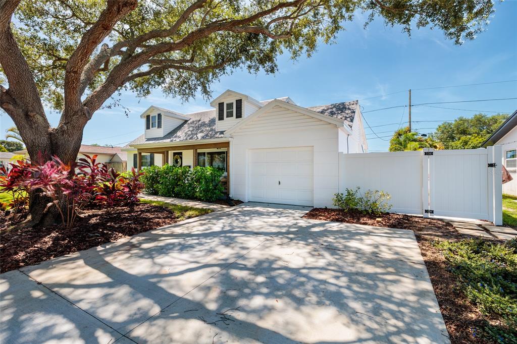 A white house with a garage, a concrete driveway, and a large tree in front — 5950 35TH AVENUE N, ST PETERSBURG, FL