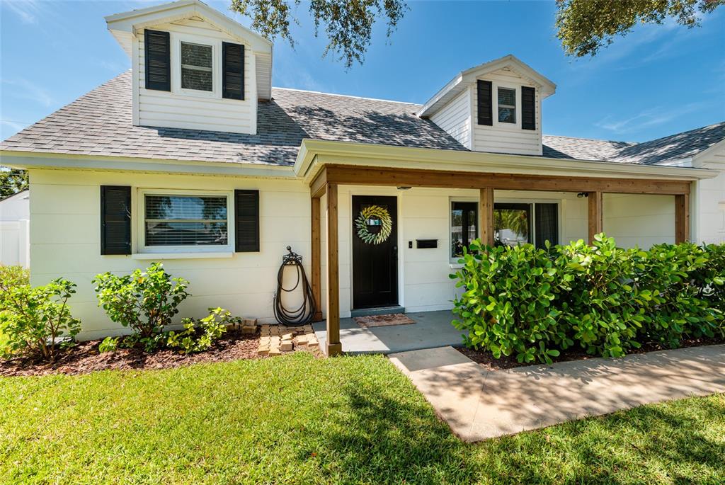 A white house with two dormers, a black front door, and a wooden porch — 5950 35TH AVENUE N, ST PETERSBURG, FL