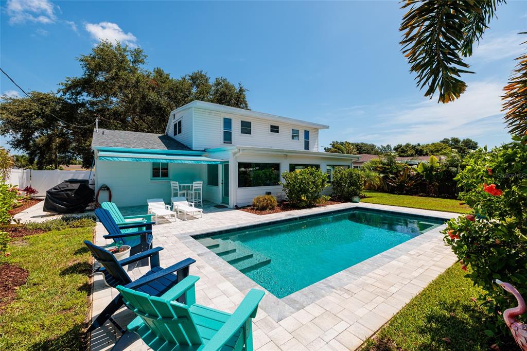 A backyard features a swimming pool, patio, and white two-story house with blue accents — 5950 35TH AVENUE N, ST PETERSBURG, FL