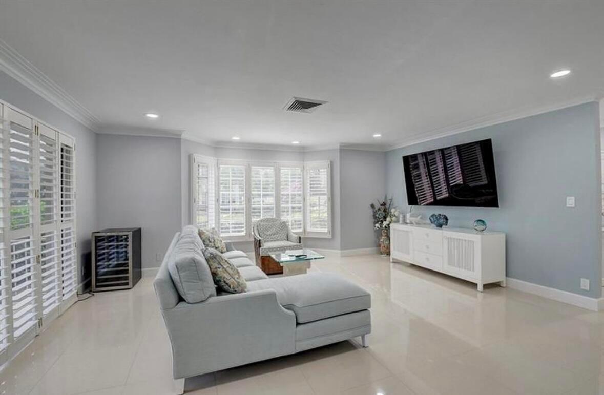 A living room features light blue walls, a sectional sofa, a white console, and shutters — 1299 S Ocean Boulevard # L5, Boca Raton FL 33432, BOCA RATON, FL