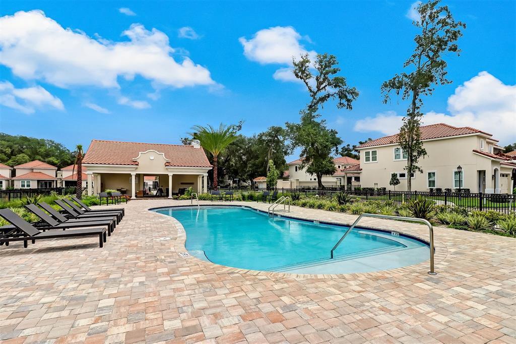 A swimming pool with lounge chairs on a paved deck in front of residential buildings — 95984 Mimosa Drive, FL 32034, FL