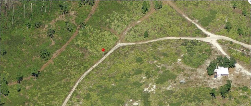 An aerial view shows a dirt road intersecting through a rural, undeveloped plot of land — HOLOPAW GROVES ROAD, ST CLOUD, FL