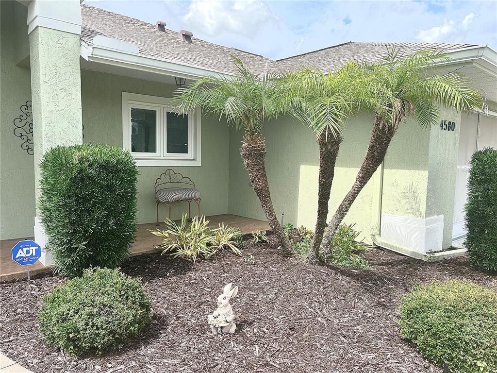 The exterior of a house features a palm tree, a small bench, and a rabbit statue — 4580 COUNTY ROAD 121D, WILDWOOD, FL