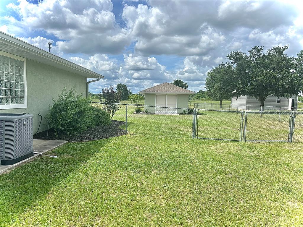 A backyard features a chain-link fence, a small shed, and a detached garage — 4580 COUNTY ROAD 121D, WILDWOOD, FL