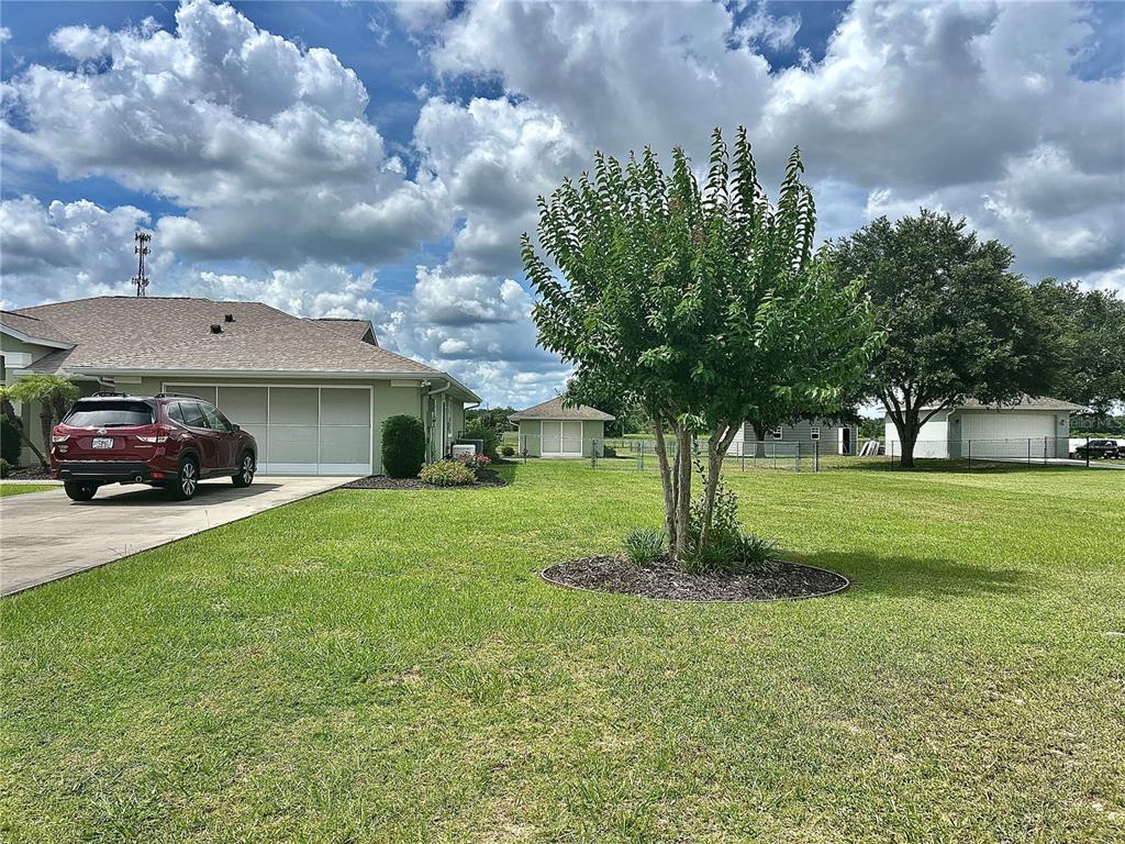 A red SUV is parked in the driveway of a house with a large lawn — 4580 COUNTY ROAD 121D, WILDWOOD, FL
