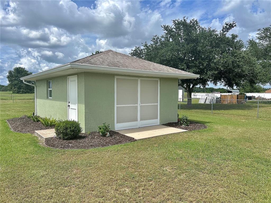 A light green detached garage with a hip roof sits on a grassy lawn — 4580 COUNTY ROAD 121D, WILDWOOD, FL