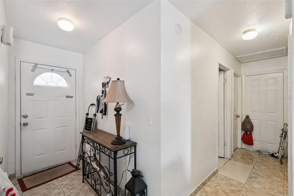 An entryway features tiled floors, a white front door, and a console table with a lamp — 6833 LONGMEADE LANE, ORLANDO, FL