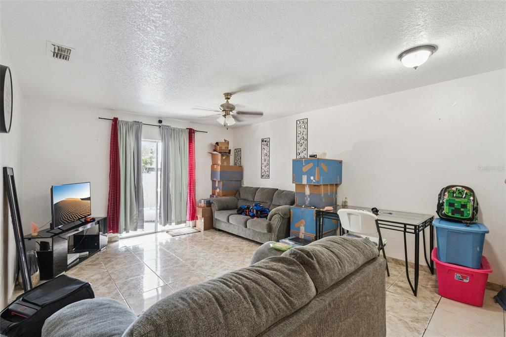 A living room features tile flooring, a ceiling fan, a sofa, and a glass-topped desk — 6833 LONGMEADE LANE, ORLANDO, FL