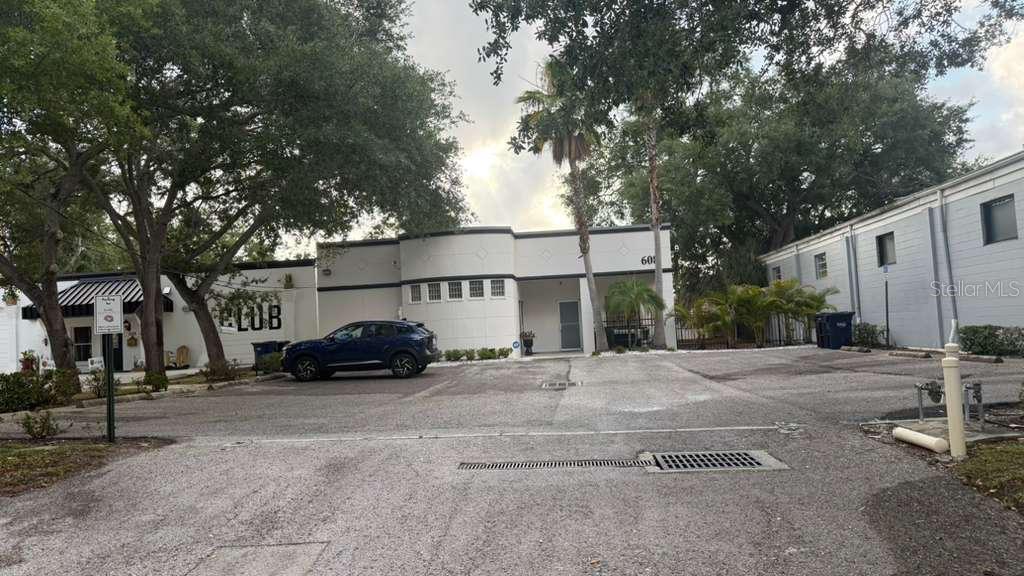A blue SUV is parked in front of a white building with a curved facade — 608 S TAMPANIA AVENUE, TAMPA, FL