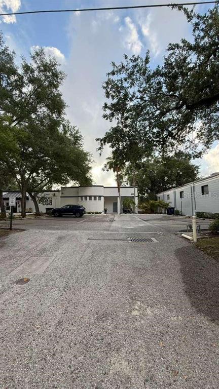 A gravel parking lot leads to a one-story commercial building surrounded by trees — 608 S TAMPANIA AVENUE, TAMPA, FL