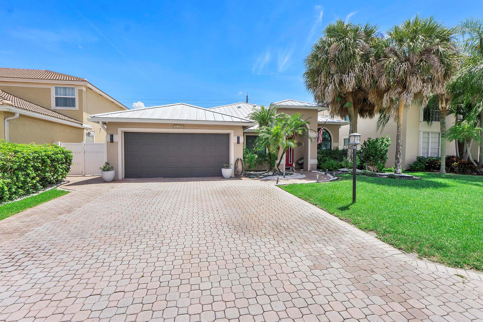 A single-story house features a paved driveway, a two-car garage, and palm trees — 12328 Saint Simon Drive, Boca Raton FL 33428, BOCA RATON, FL