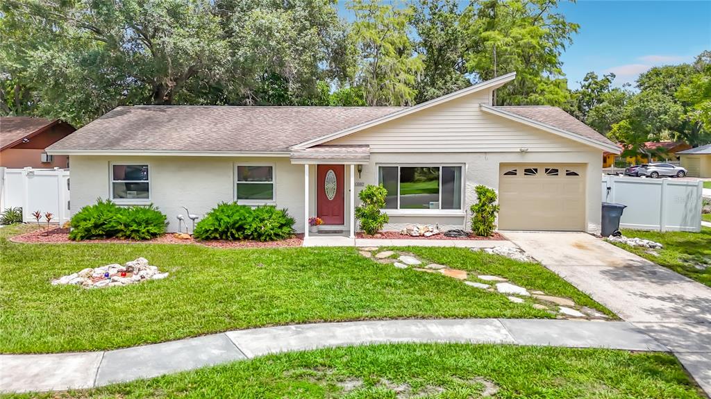 A single-story house with a beige exterior, a red front door, and an attached garage — 11007 AIRVIEW DRIVE, TAMPA, FL