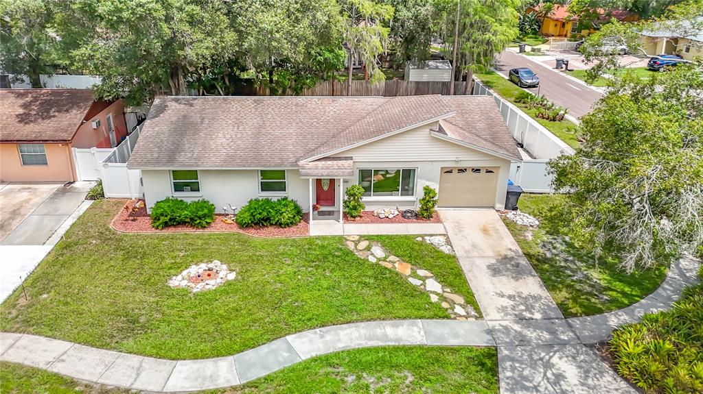 An aerial view shows a single-story house with a tan exterior, red door, and driveway — 11007 AIRVIEW DRIVE, TAMPA, FL