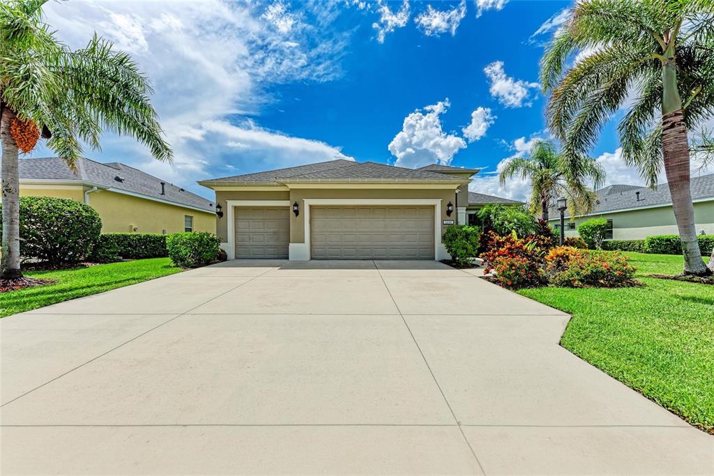A single-story house with a three-car garage and palm trees under a blue sky — 12051 FOREST PARK CIRCLE, BRADENTON, FL