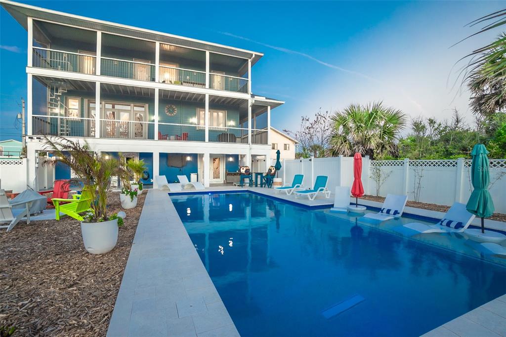 A three-story blue house with a swimming pool and a white fence in the backyard — 1807 N CENTRAL AVENUE, FLAGLER BEACH, FL