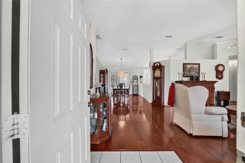 An entryway opens into a living and dining area with hardwood floors and a grandfather clock — 10036 SW 62ND CIRCLE, OCALA, FL