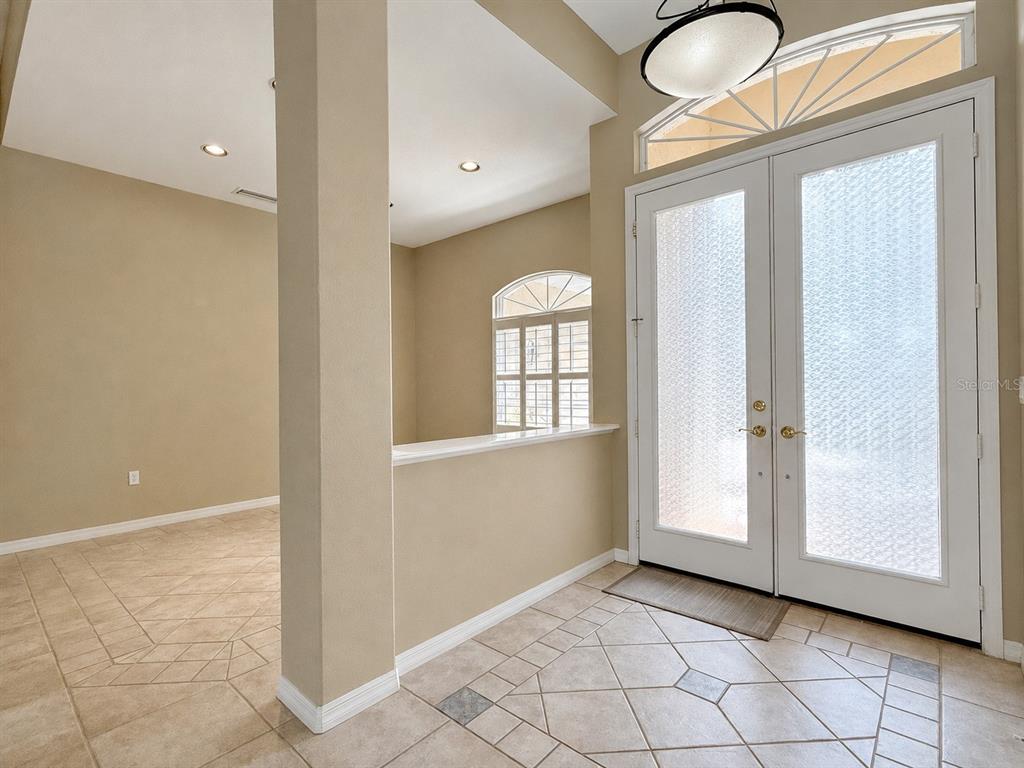 An entryway with tile flooring, a half wall, and double glass doors with a transom — 4625 SWEETMEADOW CIRCLE, SARASOTA, FL
