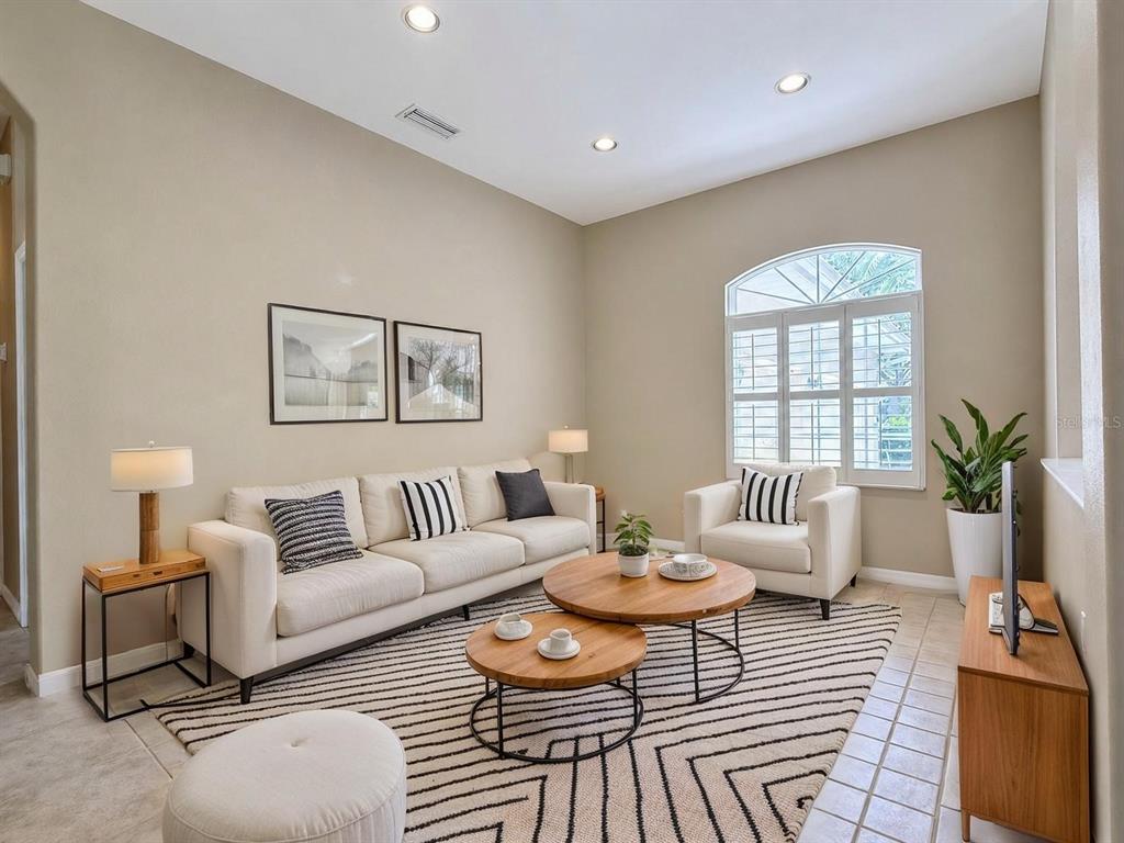 A living room features a beige sofa, two round wooden coffee tables, and a striped rug — 4625 SWEETMEADOW CIRCLE, SARASOTA, FL