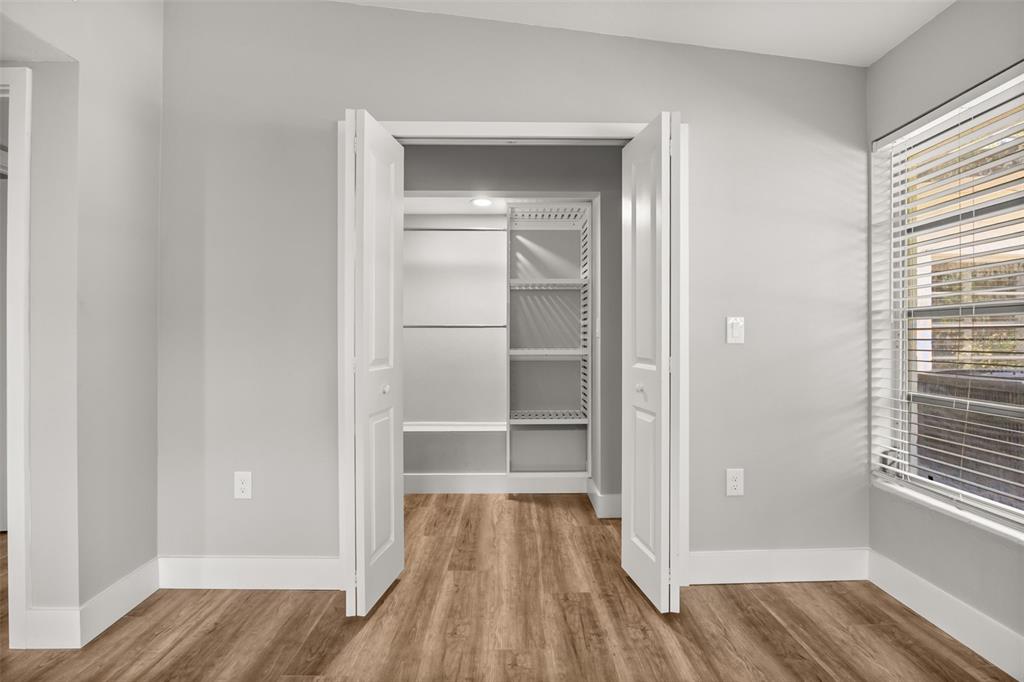 A room with light gray walls, wood-look flooring, and an open closet with built-in shelving — 1981 BLUE RIDGE ROAD, WINTER PARK, FL