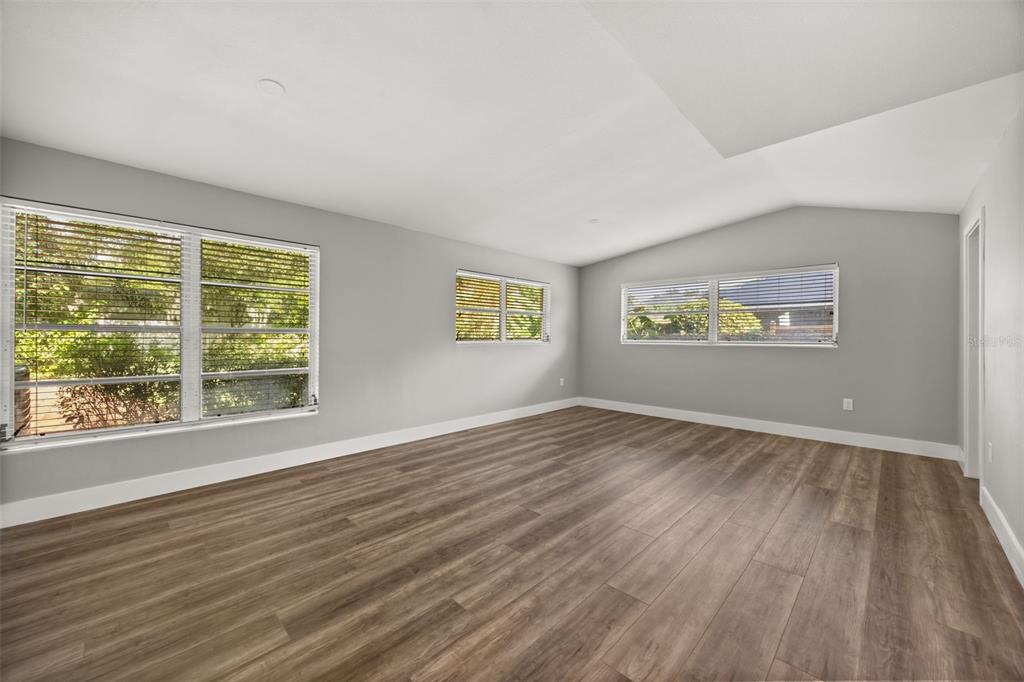 An empty room with light gray walls, wood-look flooring, and multiple windows with blinds — 1981 BLUE RIDGE ROAD, WINTER PARK, FL