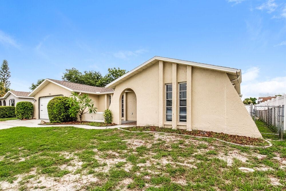A single-story house with a beige stucco exterior, a front-facing gable, and a side-entry garage — 7043 FIRESIDE DRIVE, PORT RICHEY, FL
