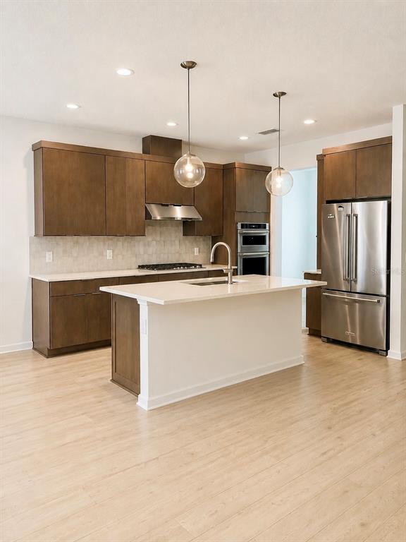A modern kitchen features wood cabinets, a white island, and stainless steel appliances — 1741 CROWNCREST DRIVE, APOPKA, FL